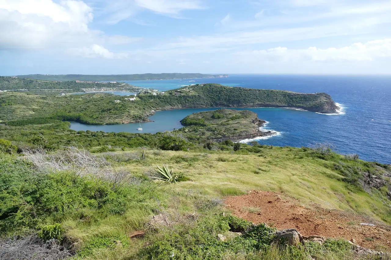 Grassy hills sloping down to a deep blue bay on the rugged coast of Antigua
