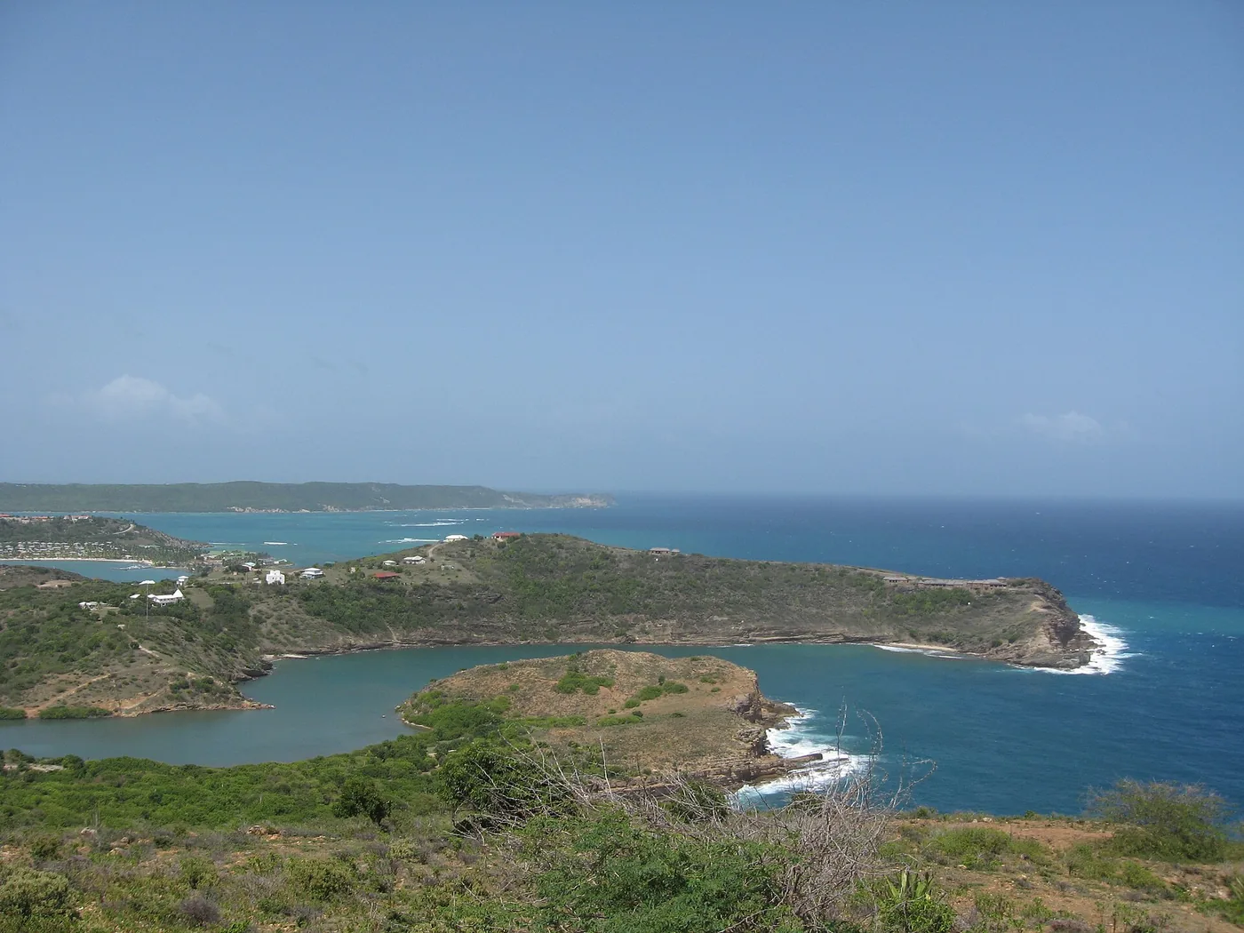 A green headland and a calm lagoon on the southern shore of Antigua with the open sea behind
